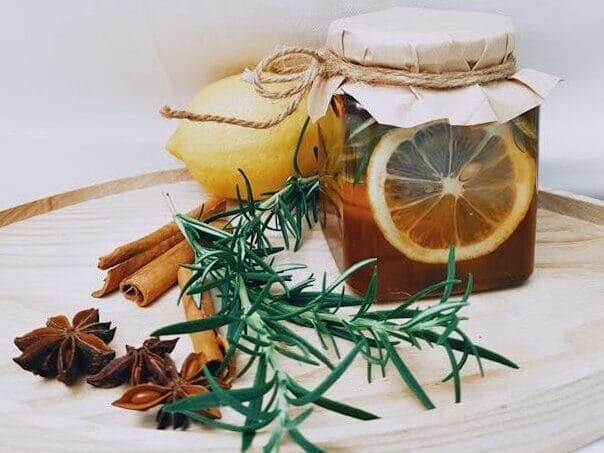 Sun Tea in a glass jar with lemon slices, cinnamon sticks, star anise, and fresh rosemary — natural homemade drink for relaxation and wellness