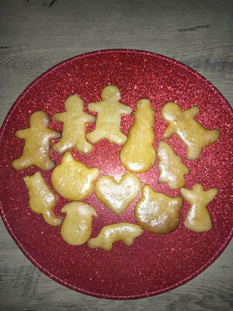 Homemade honey gingerbread biscuits in different shapes on a red sparkly plate
